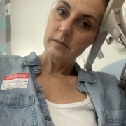 exhausted woman sitting in an ER with her head resting on a hospital bed railing